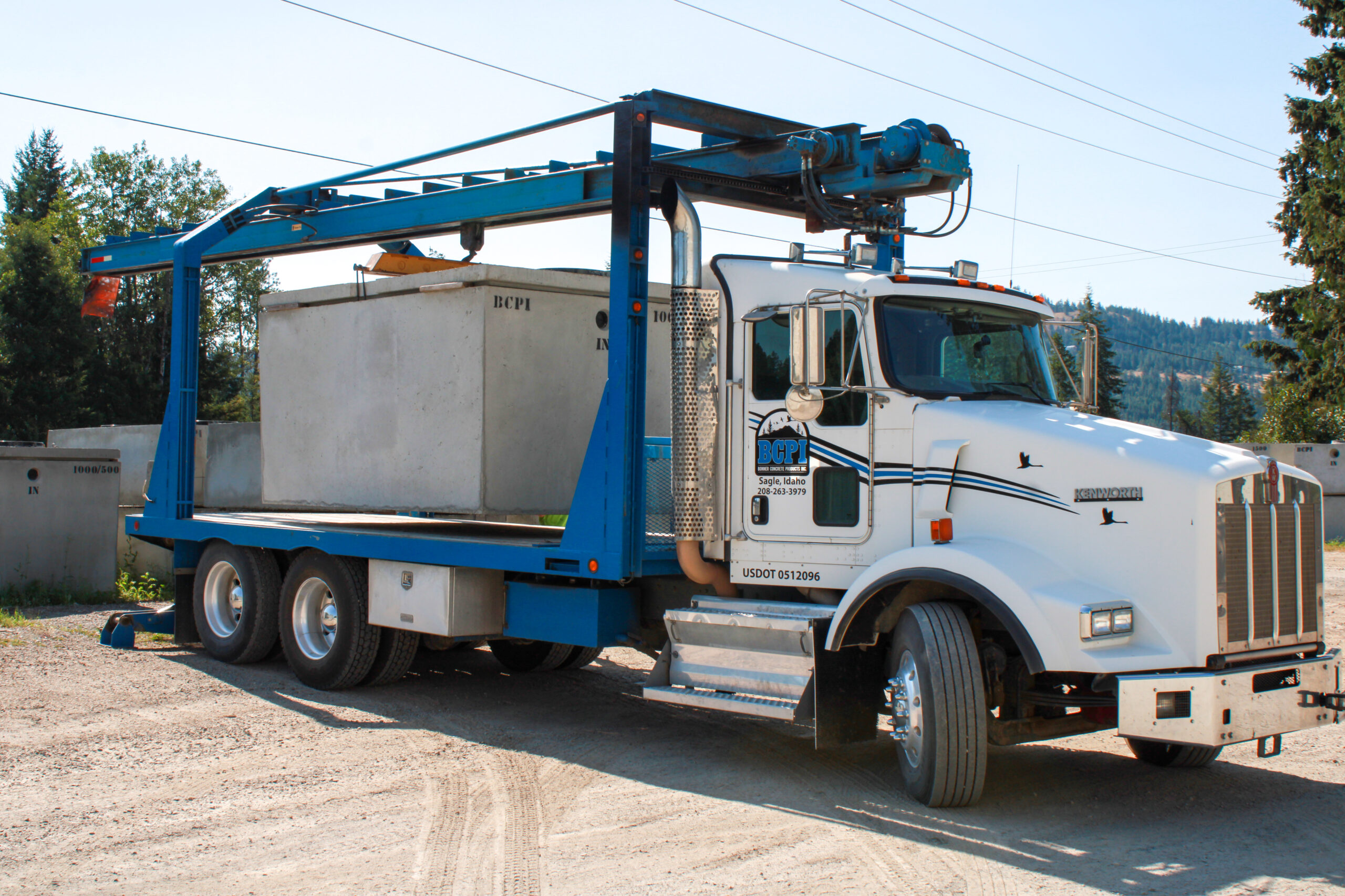 a boom truck that has a concrete septic tank on the back